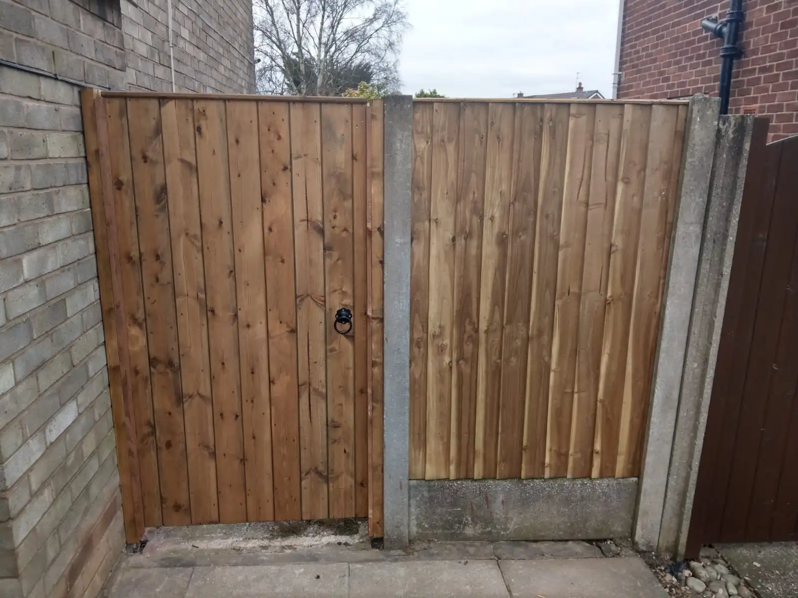 Wooden garden gate installation with concrete posts and gravel boards