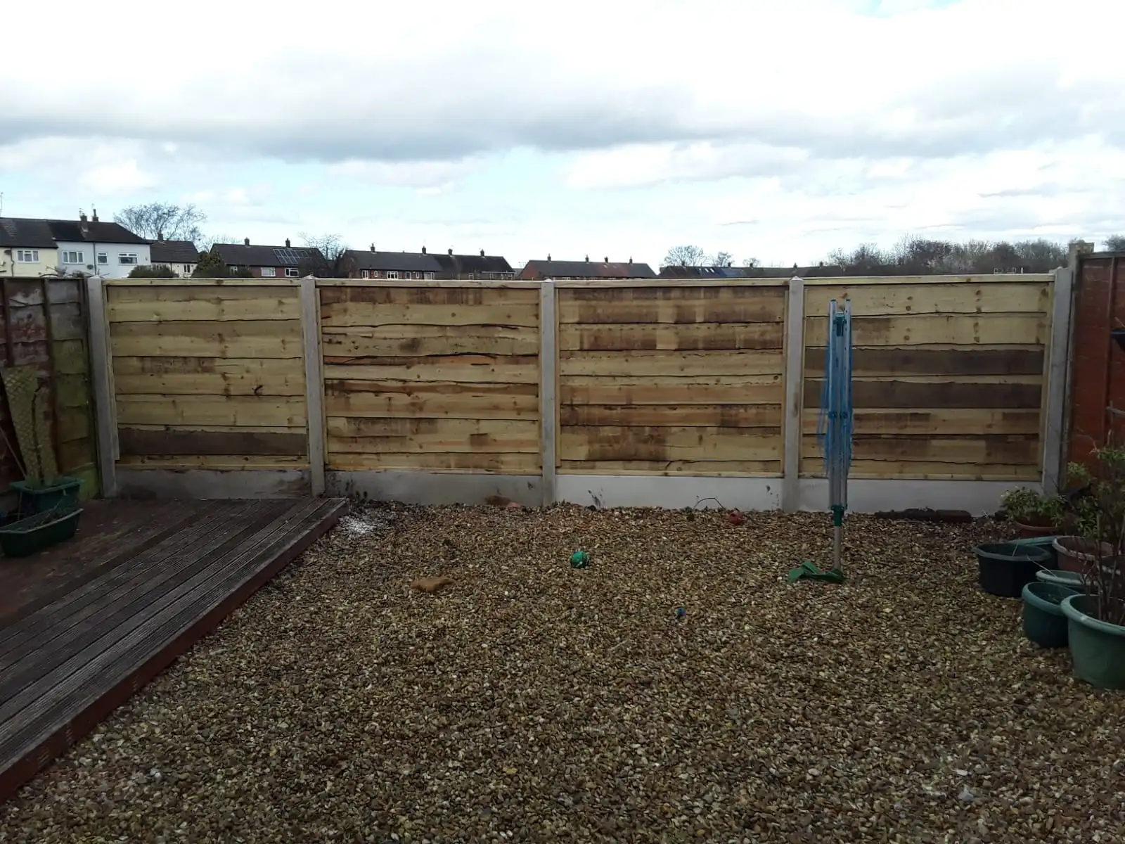 Horizontal featherboard fence panels with concrete posts in gravel garden area
