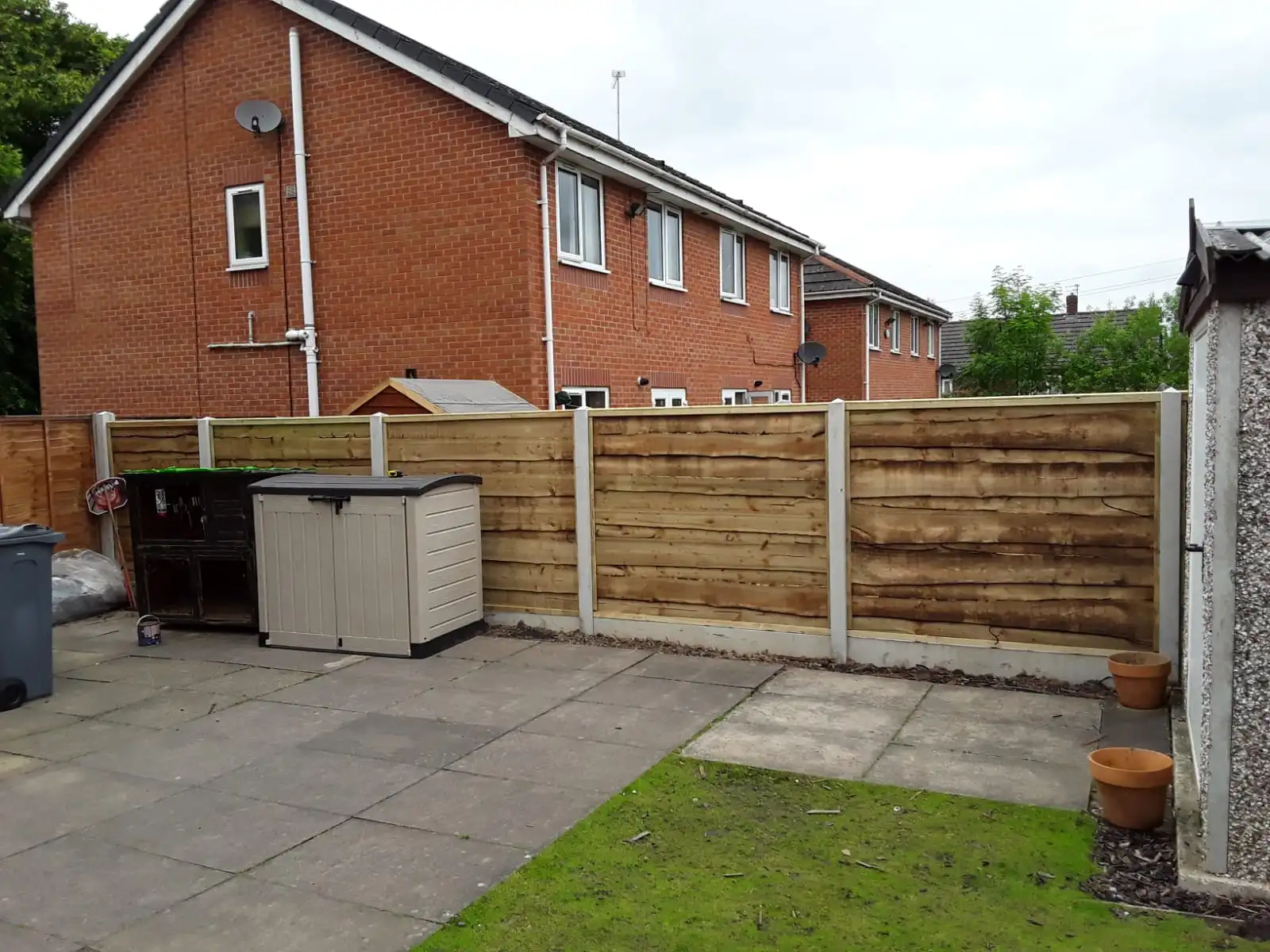 Horizontal overlap panel fencing in residential garden with paving and lawn